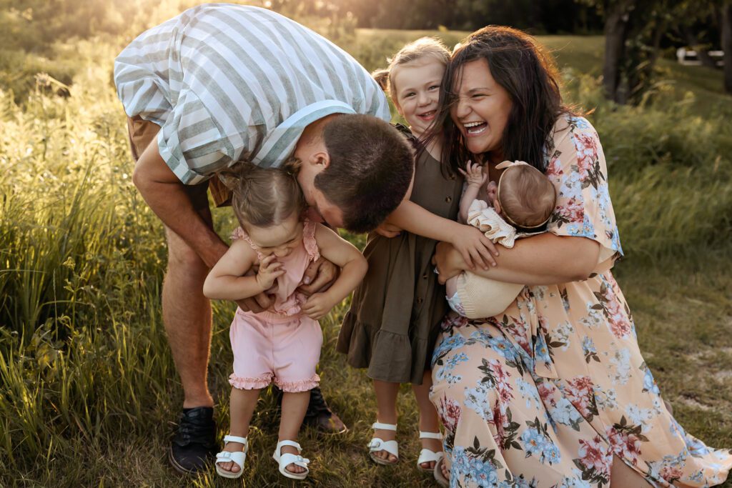 family of 5 laughing and hugging in a field during easter activity with kids in mchenry county