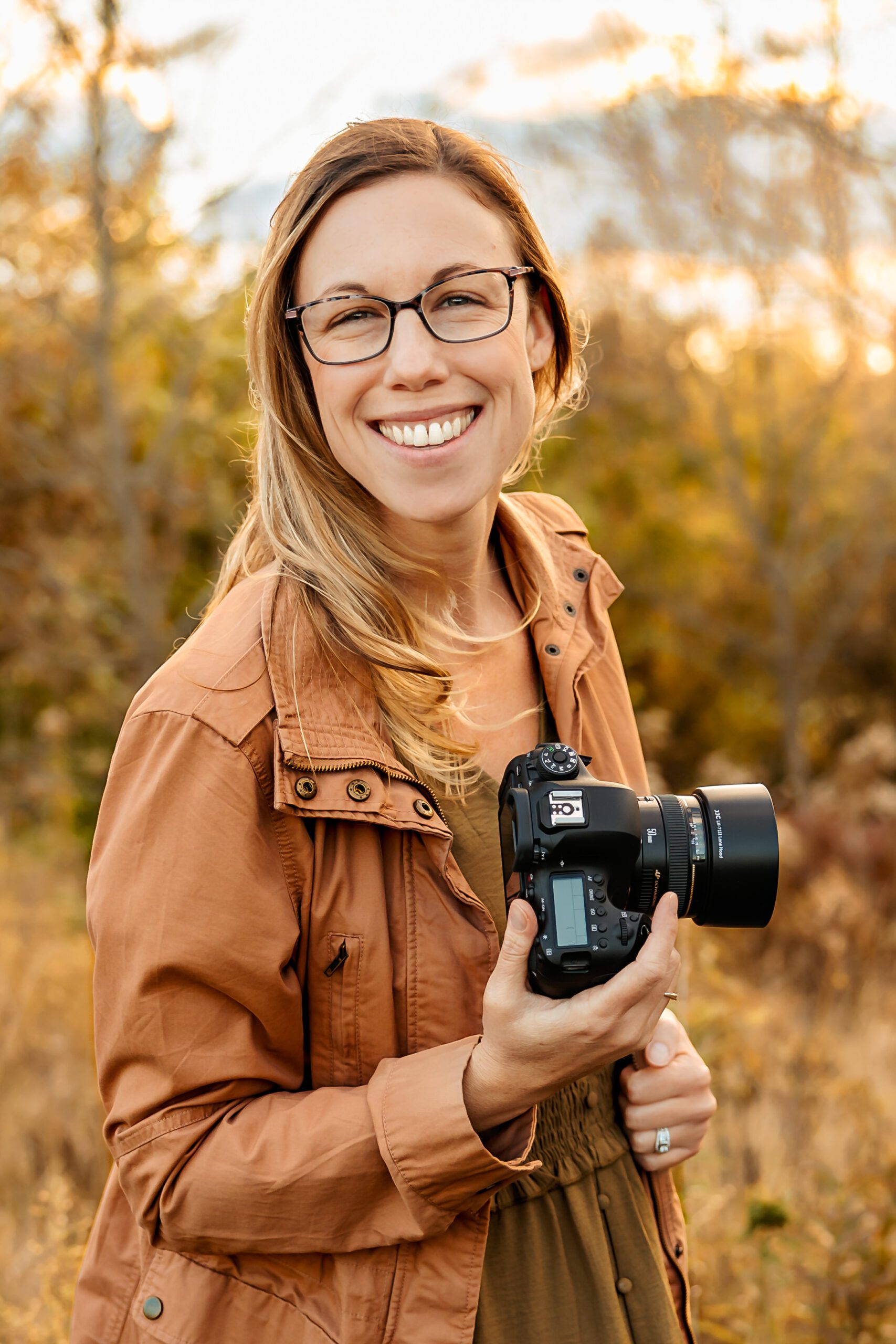 Photographer holding camera and smiling while standing in a field