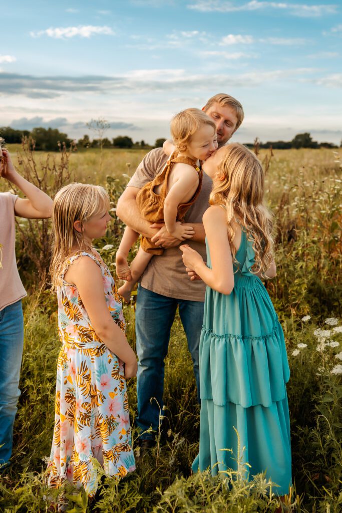 little reaching for older girl at a field outdoor photo session for family