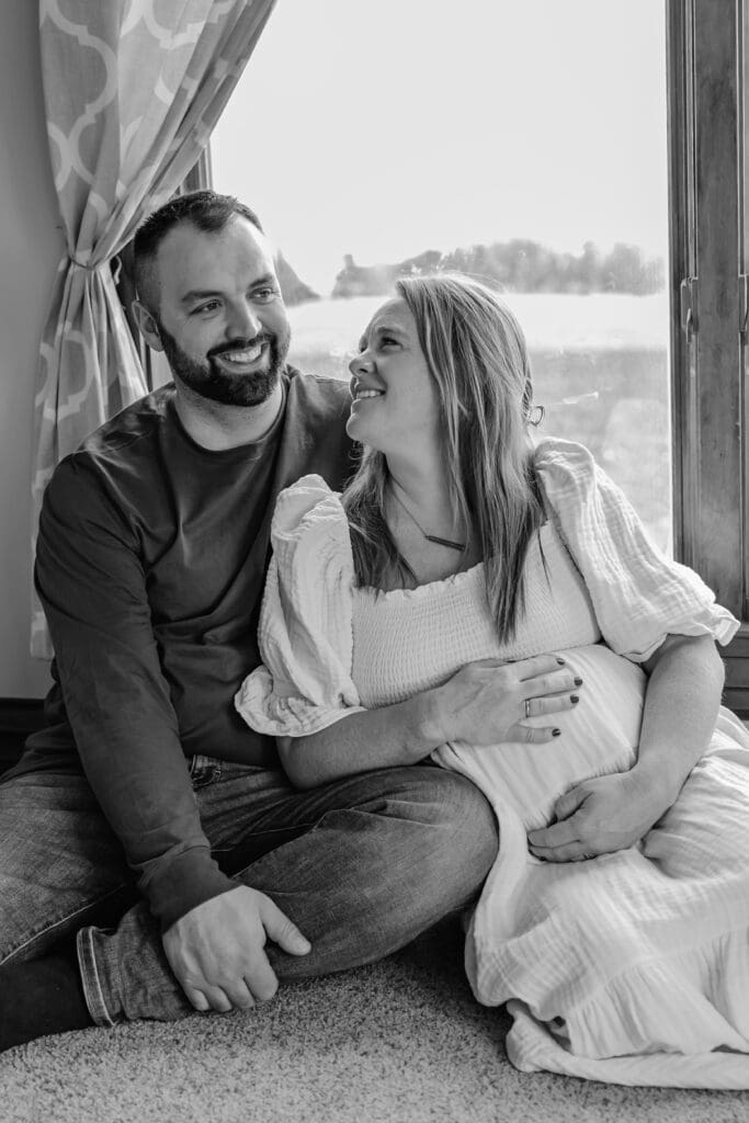 Expecting mom smiling at husband during in home maternity photoshoot