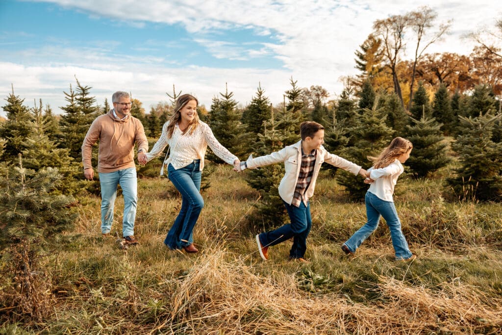 Family of 4 running through Richardson Tree Farm during family photos in the fall
