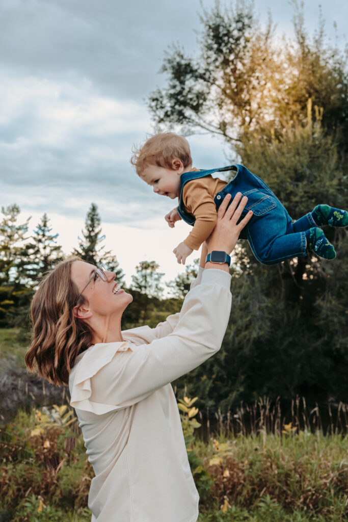 Mom lifting her toddler in the air during a fall family photo session.