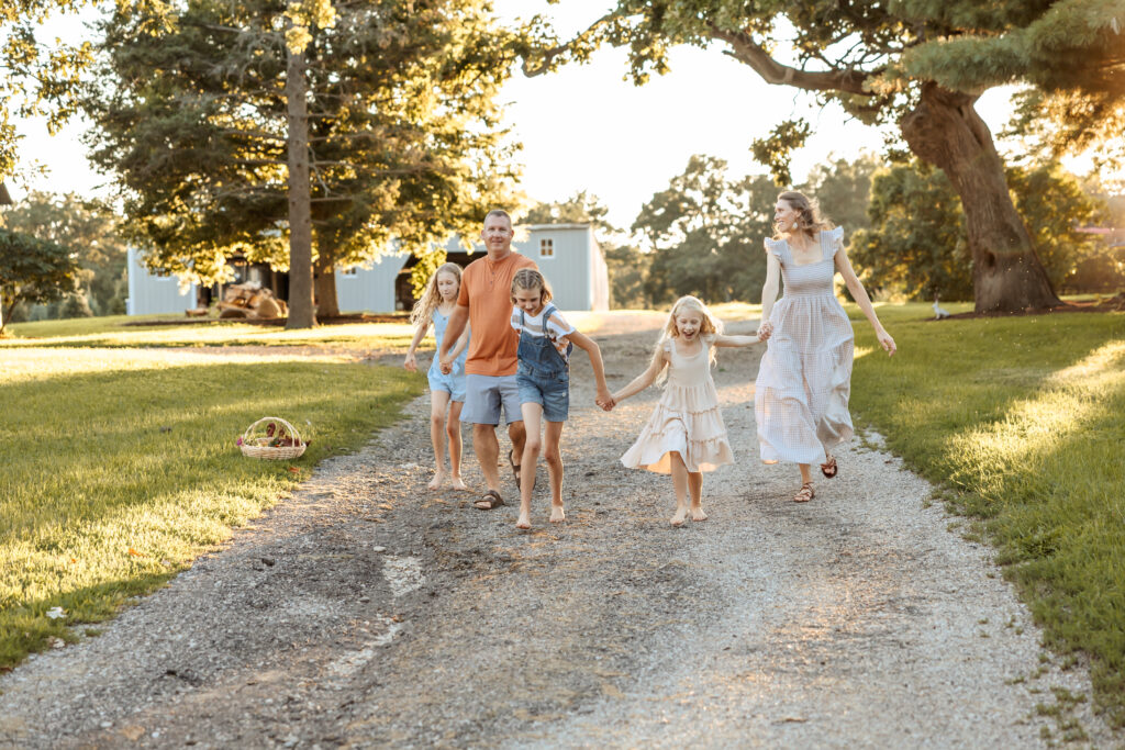 Family of 5 holding hands while running toward the camera during their at-home family photos